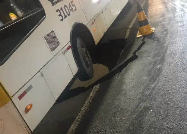 Ônibus fica com roda presa em cratera após asfalto ceder no bairro de Caminho de Areia 1